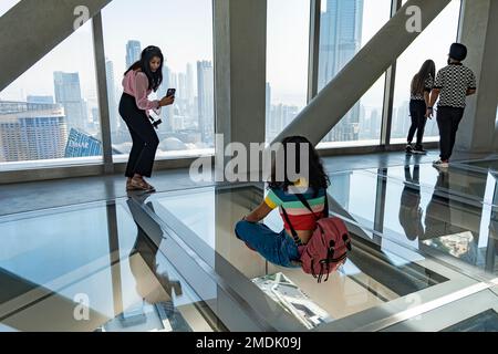 Dubai, VAE, Vereinigte Arabische Emirate. 28. November 2022. Blick in den Wolkenkratzer von Sky View. Touristen laufen auf dem Glasboden und machen Fotos in einem B Stockfoto