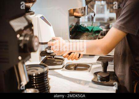 Nahaufnahme der Hand des Baristas mit der Kaffeemühle Stockfoto