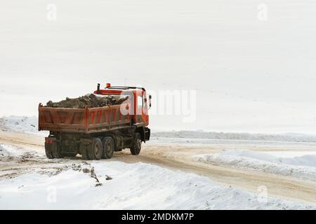 Baufahrzeug im Winter mit Schutt beladen, schneebedeckte Landschaft als Kopierplatz Stockfoto