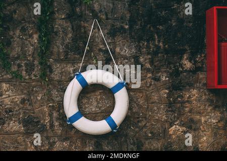 Rettungsring an der Steinwand mit schleichendem Efeu, farbiges Bild Stockfoto