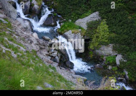 Landschaft mit Fluss. Bäume und Steine entlang der Küste den Hügel hinunter. Blick von oben Stockfoto