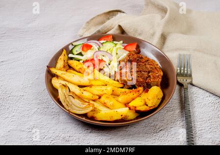 Gebratene Rippchen mit gebackenen Kartoffeln und Gewürzen auf dem Teller für ein leckeres Mittagessen. Gebackenes Schweinefleisch mit Gemüse im Backofen. Stockfoto