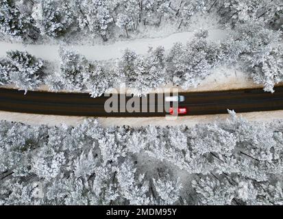 Aviemore, Schottland. 18. Januar 2023 Unvergleichlicher Blick auf den schneebedeckten Rothiemurchus Forest und Verkehr auf der B970 Road im Cairngorms National Park, Aviemore Stockfoto