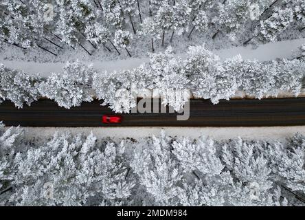 Aviemore, Schottland. 18. Januar 2023 Unvergleichlicher Blick auf den schneebedeckten Rothiemurchus Forest und Verkehr auf der B970 Road im Cairngorms National Park, Aviemore Stockfoto