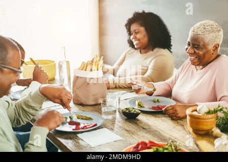 Glückliche afrikanische Familie, die zu Hause zusammen zu Mittag isst - Fokus auf das Muttergesicht Stockfoto