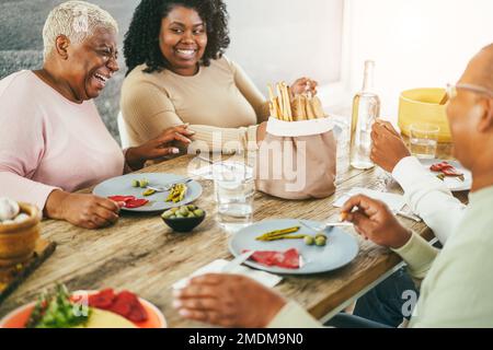Glückliche afrikanische Familie, die zu Hause zusammen zu Mittag isst - Fokus auf das Muttergesicht Stockfoto