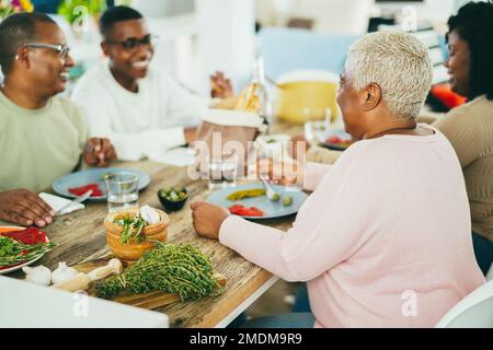 Fröhliche afrikanische Familie, die zu Hause zusammen zu Mittag isst - Fokus auf den Mutterkopf Stockfoto