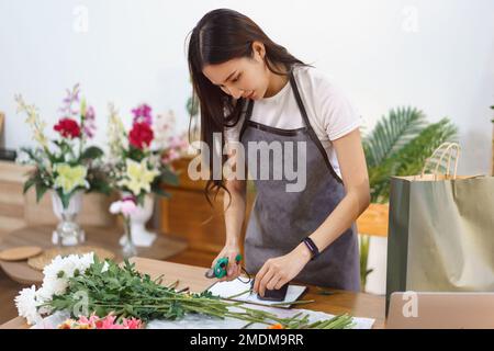 Flower Shop Konzept, Weibliche Floristin geschnitten Chrysantheme Stiele mit Schere für Blumensträuße zu machen. Stockfoto