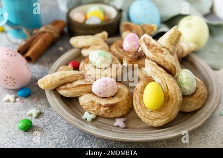 Osterhasen-förmige Brötchen pusten Gebäck mit Zimt auf einem Steintisch. Osterbackidee. Stockfoto