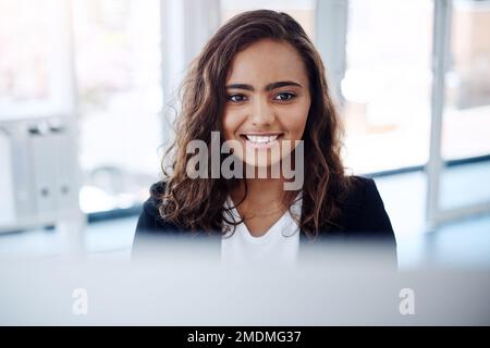 Sie arbeitet hart. Eine junge Geschäftsfrau, die an einem Computer in einem Büro arbeitet. Stockfoto