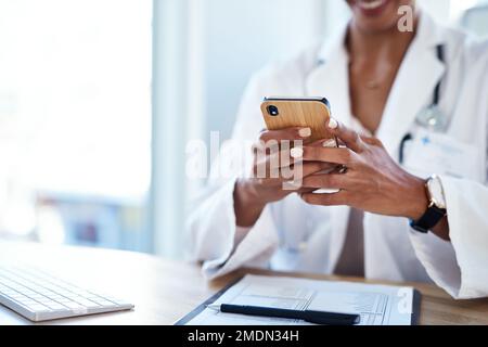 Eines der intelligentesten Hilfsmittel, das ein Arzt benutzen kann. Eine Ärztin, die ein Smartphone in ihrem Sprechzimmer benutzt. Stockfoto