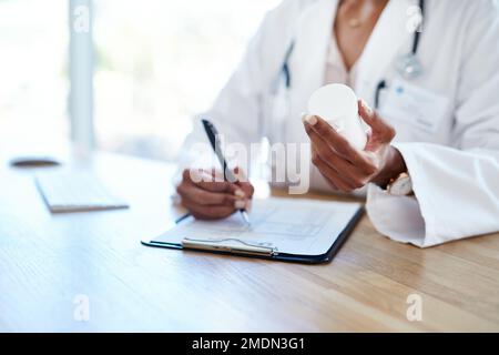 Ihre Gesundheit liegt in ihren Händen. Eine junge Ärztin, die in ihrem Sprechzimmer ein Rezept ausfüllt. Stockfoto