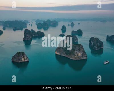 Verträumt Sonnenuntergang unter den Felsen der Halong Bay, Vietnam Stockfoto