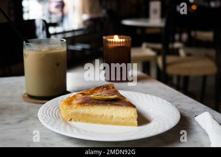 Käse-Zitronenkuchen mit Eiskaffee auf dem Tisch im Restaurant. Stockfoto