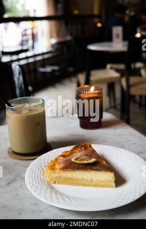 Käse-Zitronenkuchen mit Eiskaffee auf dem Tisch im Restaurant. Stockfoto