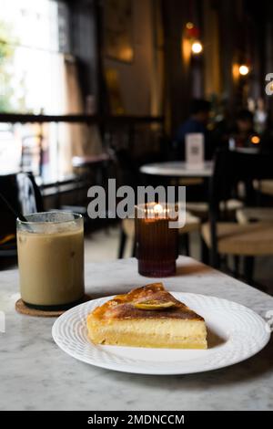 Käse-Zitronenkuchen mit Eiskaffee auf dem Tisch im Restaurant. Stockfoto