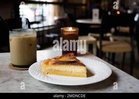 Käse-Zitronenkuchen mit Eiskaffee auf dem Tisch im Restaurant. Stockfoto