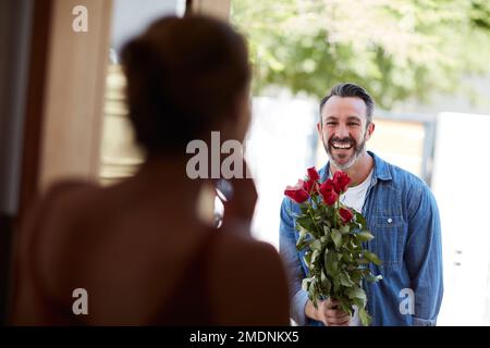 Er macht ihr immer einen besonderen Valentinstag. Ein attraktiver reifer Mann, der seine Freundin mit einem Strauß Rosen überraschte. Stockfoto