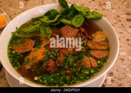 Pho Bo oder vietnamesische Suppe mit Rindfleisch und Fleischbällchen, serviert in einer weißen Schüssel. Stockfoto