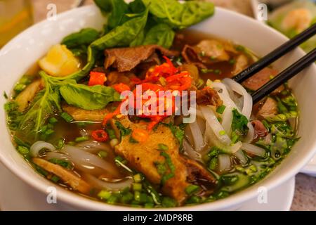 Pho Bo oder vietnamesische Suppe mit Rindfleisch und Fleischbällchen, serviert in einer weißen Schüssel. Stockfoto