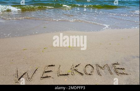 Handschreiber-Inschrift Welkome-Wort über tropischen Sandstrand, Reise-Konzeptkarte für Urlaub. Stockfoto