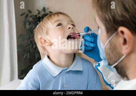 Der Junge bekommt Polio-Tropfen. Arztmachen zum Kind orale Schutzimpfung gegen Infektionen. Kleiner blonder Haarjunge im Krankenhaus. Kindergesundheitsfürsorge und Kinderkrankheiten Stockfoto