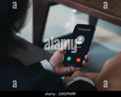 Eingehender Anruf mit unbekanntem Anrufer, böswilliges Anrufkonzept. Unbekannte Nummer wird auf dem Smartphone in der Hand eines Geschäftsmanns angezeigt. Spam Stockfoto