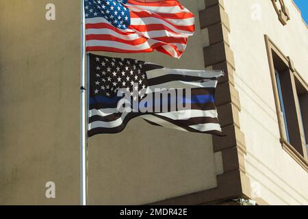 Dünne blaue Strafverfolgungsflagge, die auf einem Stab unter der Flagge der Vereinigten Staaten in einem Viertel von New York City fliegt Stockfoto