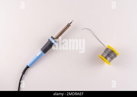 Selektiver Fokus Draufsicht des Lötkolbens und der Lötdrahtspule isoliert auf weißem Hintergrund mit Textbereich. Stockfoto