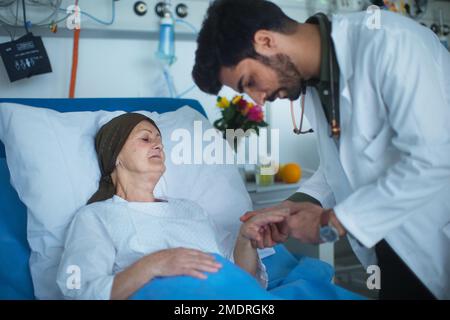 Junger Arzt aus dem Nahen Osten, der Krebspatienten im Krankenhaus untersucht. Stockfoto