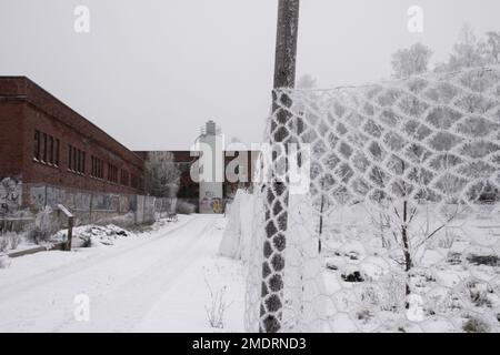 Fotoshooting in einer alten Fabrik, Graffiti-Kunstmauern, alten Industriebauten und eiskaltem Winterwetter. Schnee auf dem Boden Stockfoto