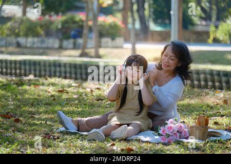 Asiatische Großmutter und Enkelin umarmen sich gemeinsam im Park. Hobbys und Freizeit, Lifestyle, Familienleben, Happiness Moment Konzept Stockfoto