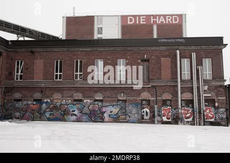 Fotoshooting in einer alten Fabrik, Graffiti-Kunstmauern, alten Industriebauten und eiskaltem Winterwetter. Schnee auf dem Boden Stockfoto