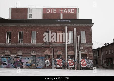 Fotoshooting in einer alten Fabrik, Graffiti-Kunstmauern, alten Industriebauten und eiskaltem Winterwetter. Schnee auf dem Boden Stockfoto