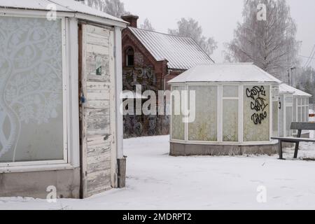 Fotoshooting in einer alten Fabrik, Graffiti-Kunstmauern, alten Industriebauten und eiskaltem Winterwetter. Schnee auf dem Boden Stockfoto