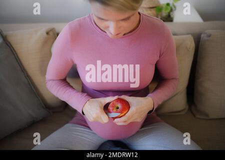 Aus dem Blickwinkel einer schwangeren Frau, die Apfel schneidet. Stockfoto