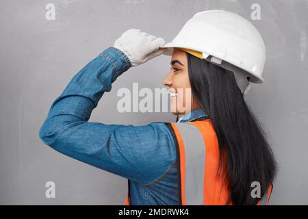Porträt einer südasiatischen Bauarbeiterin, die ihren Hut nach links kippt Stockfoto