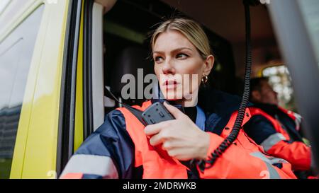 Porträt einer jungen Ärztin, die im Krankenwagen in ein Walkie-Talkie sitzt und spricht. Stockfoto
