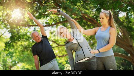 Ihre Vitalität hat sie nie verlassen. Ein Lehrer, der ein Seniorenpaar in einem Yoga-Kurs leitet. Stockfoto