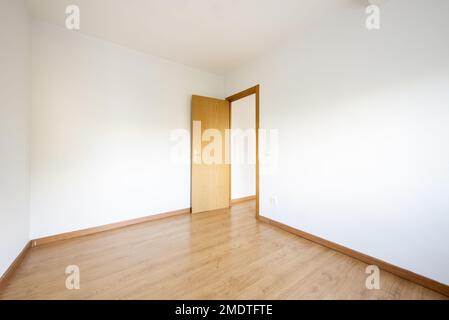 Kleiner leerer Raum mit Eichenlaminatboden mit passenden Sockelleisten und Türen Stockfoto