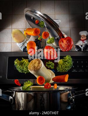 Explodierend.fliegendes Gemüse über einem Topf in der Küche.gesunde Gemüsesuppe voller Vitamine.Lasst uns gesund essen! Stockfoto