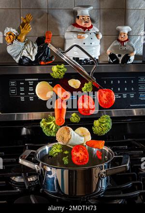 Explodierend.fliegendes Gemüse über einem Topf in der Küche.gesunde Gemüsesuppe voller Vitamine.Lasst uns gesund essen! Stockfoto