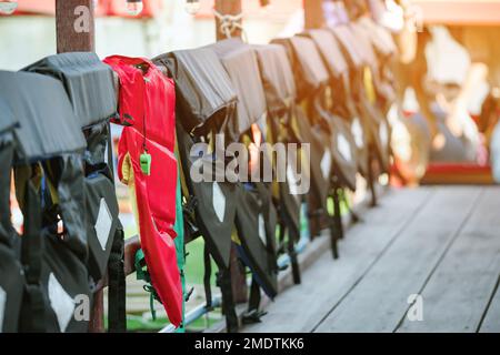 Eine grüne Pfeife mit roter Lebensjacke, die am Geländer um den Gehweg hängt, damit die Passagiere sicher an den Docks sind. Stockfoto