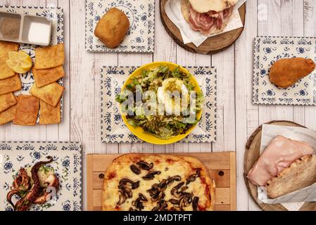 Auswahl typischer italienischer Gerichte mit einem Burrata-Salat mit Nüssen, Focaccia, sizilianischen Mortadella-Sandwiches und gegrilltem Oktopus Stockfoto