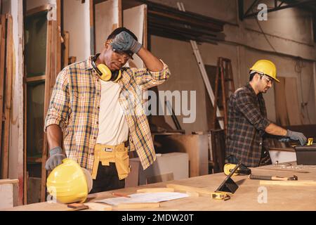 Müde Müdigkeit harter Arbeiter in der Holzwerkstatt schwitzt bei heißem Wetter Stockfoto