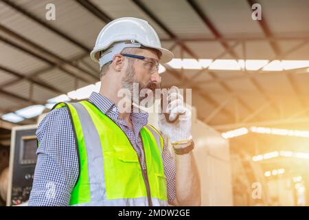 hispanische, indische, männliche, leitende Ingenieurarbeiterin, die in der Schwerindustrie für intelligente Funkrufe arbeitet Stockfoto