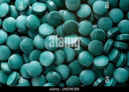 Green Organic Spirulina in Algen Pillen Tabletten Bambusholzlöffel reich an Eisen Nahaufnahme Super Food Konzept gesund. Stockfoto