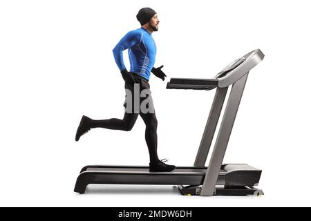 Durchgehende Profilaufnahme eines Mannes, der Winterkleidung trägt und auf einem Laufband trainiert, isoliert auf weißem Hintergrund Stockfoto