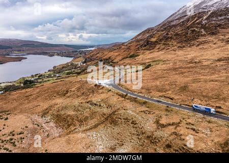 DUNLEWEY, GRAFSCHAFT DONEGAL, IRLAND - JANUAR 16 2023 : die R251 liegt neben dem schneebedeckten Berg Errigal, dem höchsten Berg in Donegal. Stockfoto