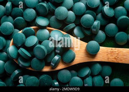 Green Organic Spirulina in Algen Pillen Tabletten Bambusholzlöffel reich an Eisen Nahaufnahme Super Food Konzept gesund. Stockfoto